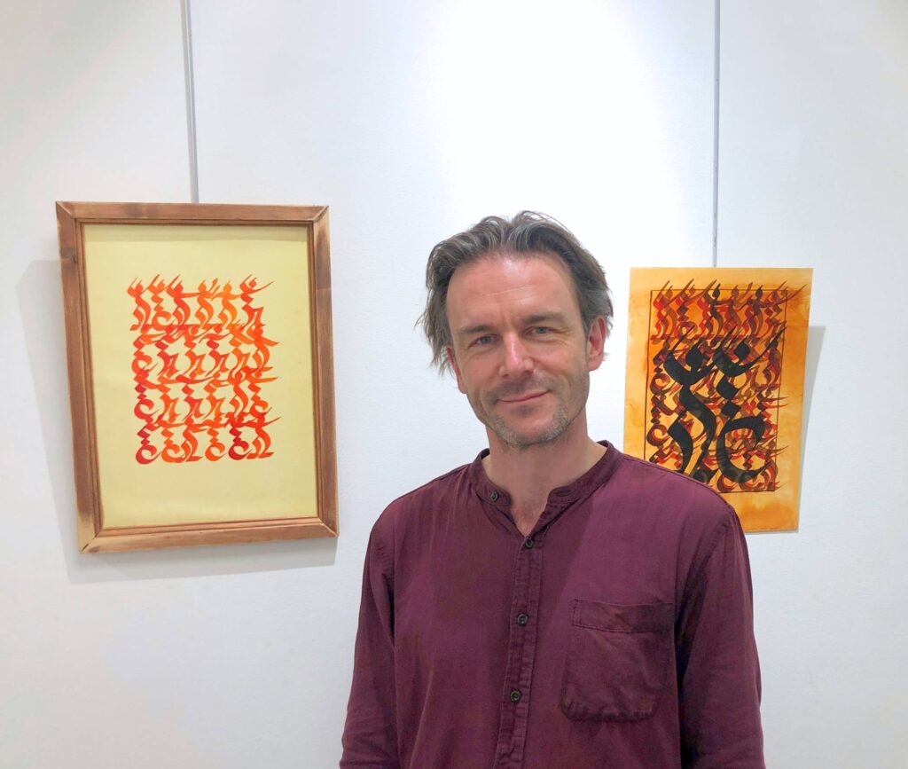 Richard Frost beside his art exhibition.