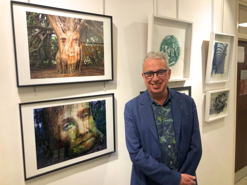 Artist standing in front of art work they created for the exhibition.